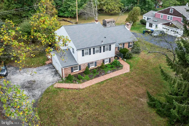an aerial view of a house with swimming pool and large trees