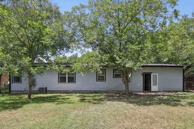 a backyard of a house with plants and large tree