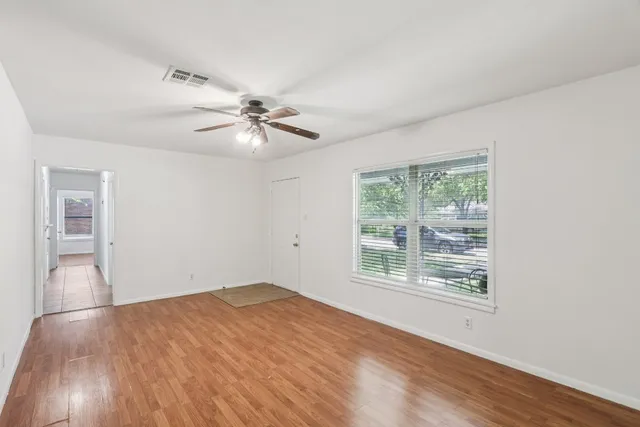 a view of an empty room with wooden floor and a window