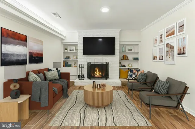 a view of an empty room with wooden floor and a fireplace