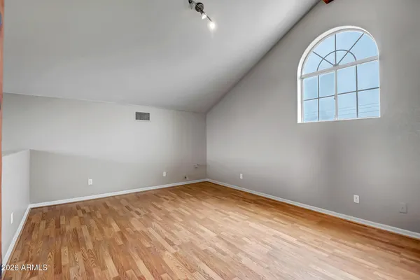 a view of a big room with wooden floor a ceiling fan and windows