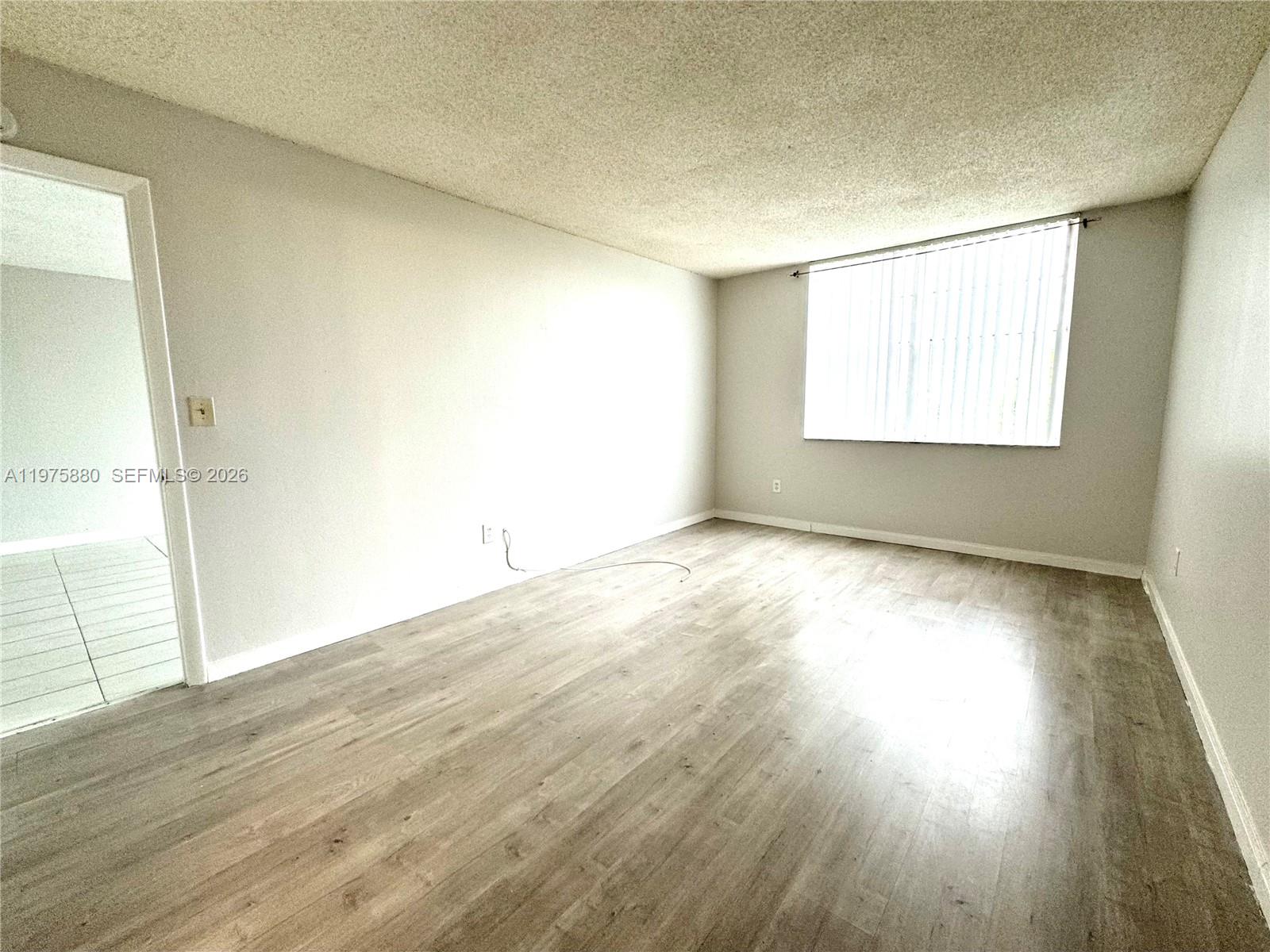 484 Northwest 165th St Road, Unit A411 Miami, FL 33169 - Photo 11 of 18 an empty room with wooden floor and windows
