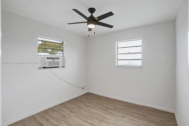 an empty room with wooden floor and ceiling fan