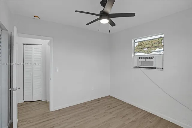 an empty room with wooden floor fan and windows