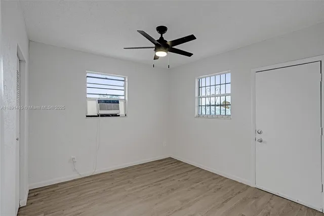 a view of empty room with wooden floor and fan