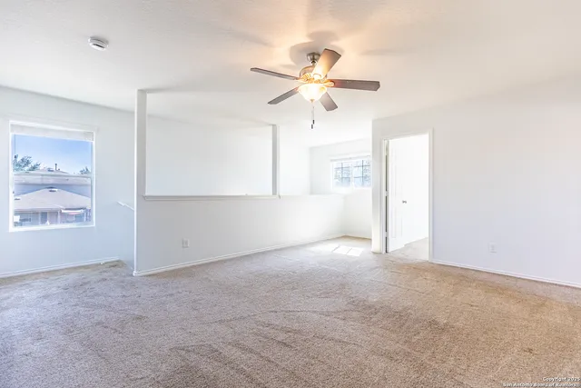 an empty room with windows and fan