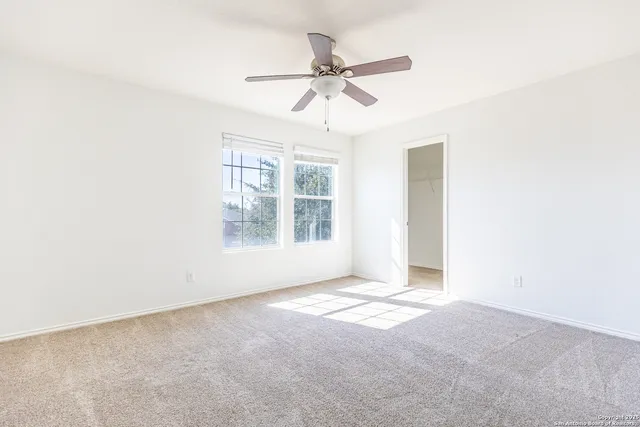 an empty room with windows and fan