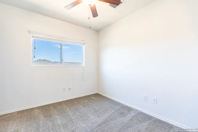 an empty room with a ceiling fan and a window