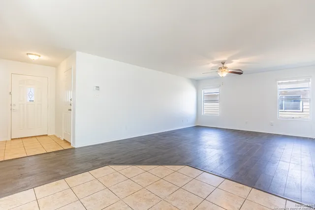 an empty room with wooden floor chandelier and windows
