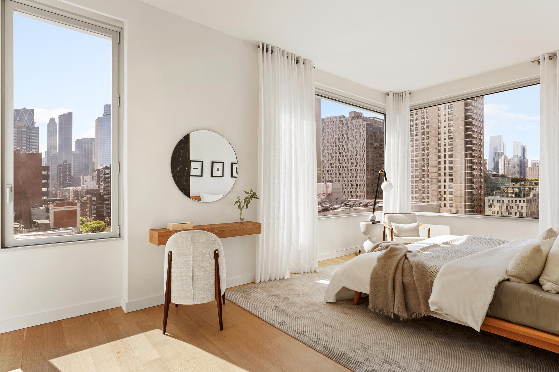 611 West 56th Street, Unit 12 Manhattan, NY 10019 - Photo 3 of 24 a spacious bedroom with a bed a window and a chandelier