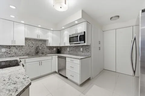 a kitchen with granite countertop white cabinets and stainless steel appliances