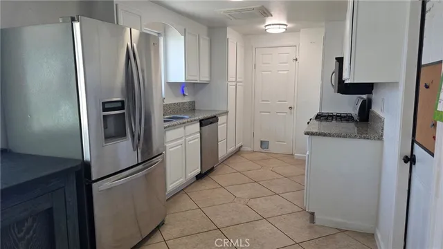 a kitchen with stainless steel appliances granite countertop a refrigerator a sink a stove and white cabinets