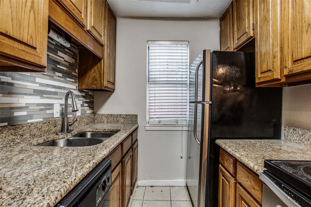 a kitchen with a granite countertop sink a refrigerator and cabinets