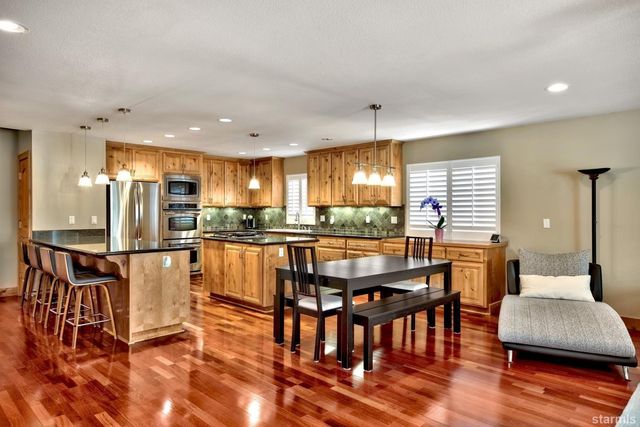 a kitchen with stainless steel appliances granite countertop a kitchen island a stove a table and chairs