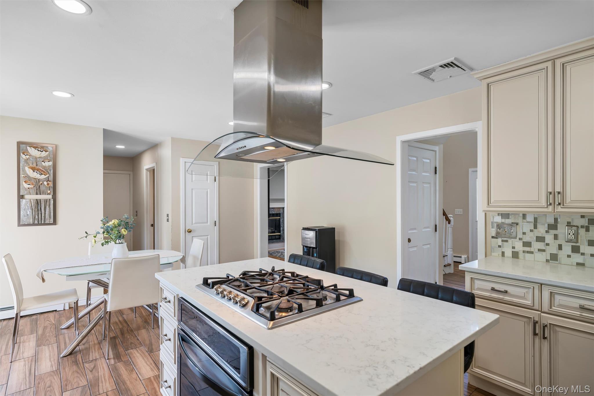 36 Lexington Drive Newburgh, NY 12550 - Photo 15 of 50 Kitchen with cream cabinets, oven, stainless steel gas cooktop, island range hood, and backsplash