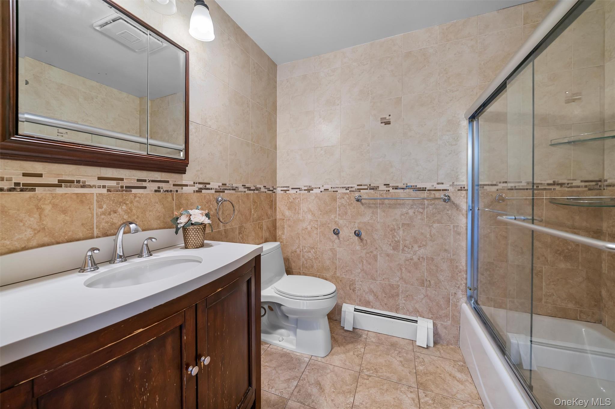 36 Lexington Drive Newburgh, NY 12550 - Photo 36 of 50 Bathroom featuring tile walls, baseboard heating, toilet, vanity, and combined bath / shower with glass door