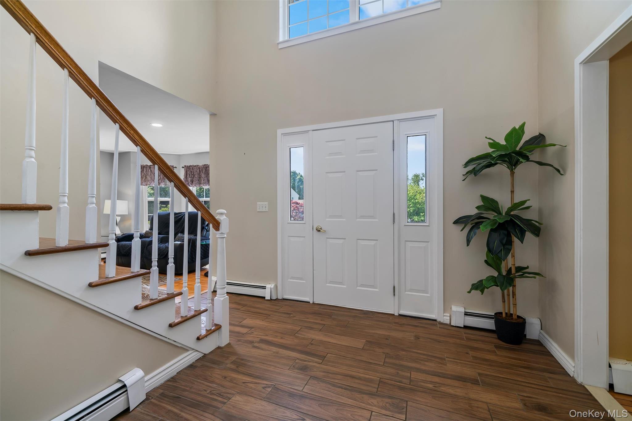 36 Lexington Drive Newburgh, NY 12550 - Photo 6 of 50 Entrance foyer with a baseboard radiator, a towering ceiling, dark wood-style floors, stairs, and healthy amount of natural light