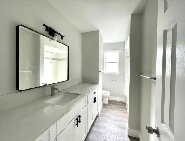 a bathroom with a granite countertop sink mirror and a toilet