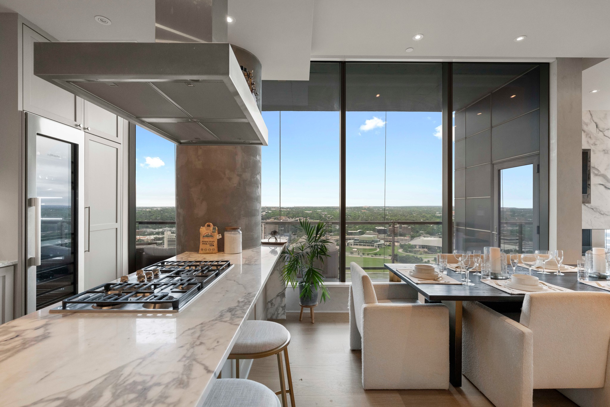 210 Lavaca Street, Unit 2706 Austin, TX 78701 - Photo 22 of 32 Gourmet kitchen featuring a marble-patterned countertop island with a built-in gas cooktop, stainless steel ventilation hood, integrated wine refrigerator, and custom cabinetry