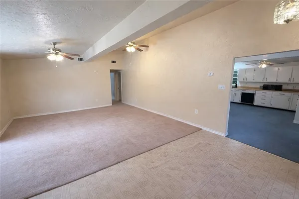 an empty room with a chandelier fan and wooden floor