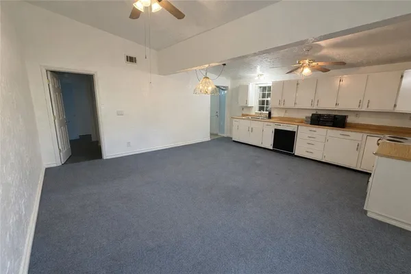 a large white kitchen with a stove a sink dishwasher and a refrigerator with wooden floor
