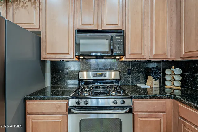 a kitchen with granite countertop white cabinets and stainless steel appliances