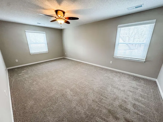 an empty room with windows and fan