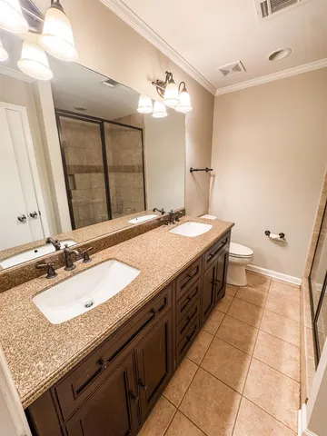 a spacious bathroom with a granite countertop double vanity sink a mirror and a