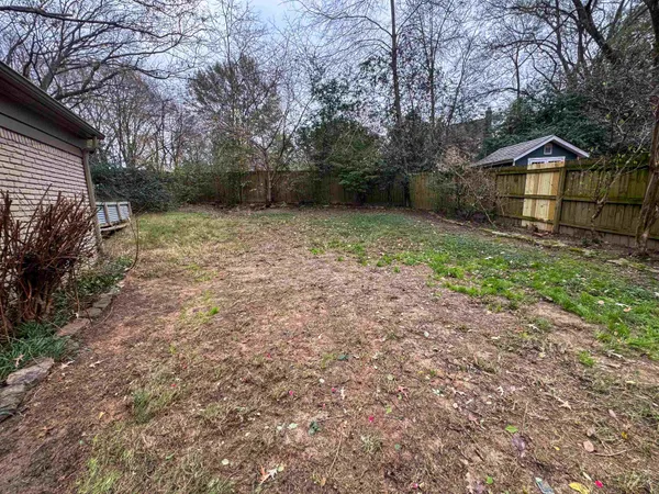 a view of backyard of house with wooden fence