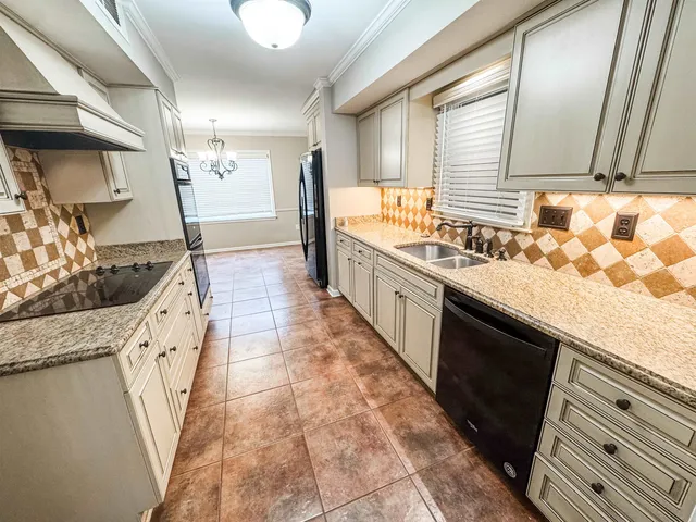 a large kitchen with granite countertop a sink a stove and cabinets