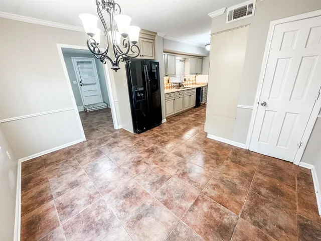 a view of a refrigerator in kitchen and an empty room