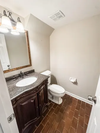 a bathroom with a granite countertop sink toilet and mirror