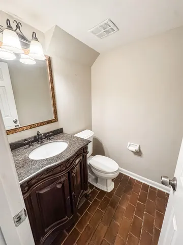 a bathroom with a granite countertop sink toilet and mirror