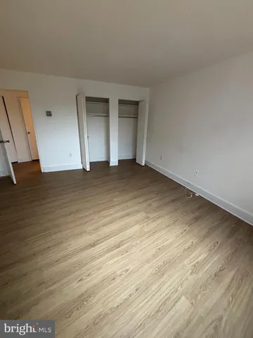 a view of an empty room with wooden floor and closet