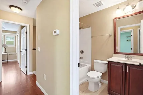 a view of an empty room with wooden floor and a bathroom
