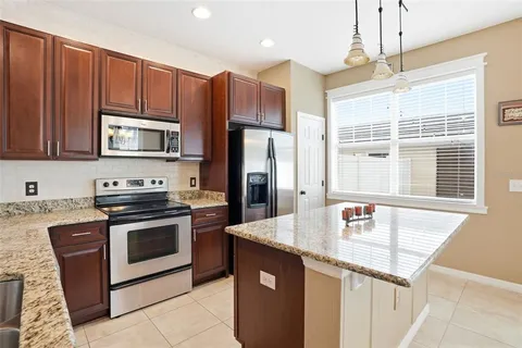 a kitchen with stainless steel appliances granite countertop a refrigerator a sink a stove a microwave oven and a center island