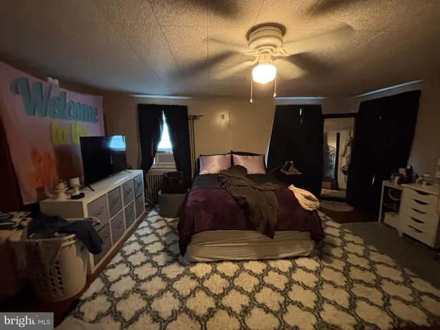 a spacious bedroom with a bed a mirror on dresser and a flat screen tv
