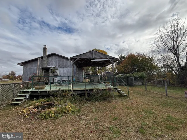 a backyard of a house with table and chairs under an umbrella