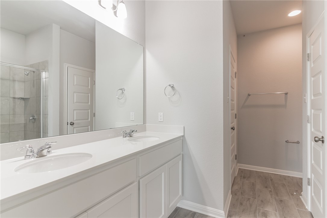 129 Wild Wind Trail Jarrell, TX 76537 - Photo 11 of 27 Primary bathroom has double vanities with ample counter top space. Large walk in closet behind door on left. Linen closet behind door on right. Private commode area.