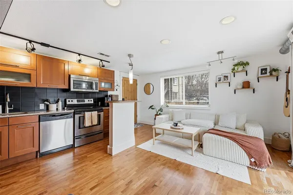 a living room with stainless steel appliances furniture and a kitchen view