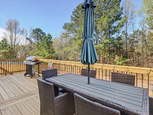 a view of a deck with table and chairs a barbeque with wooden floor and fence