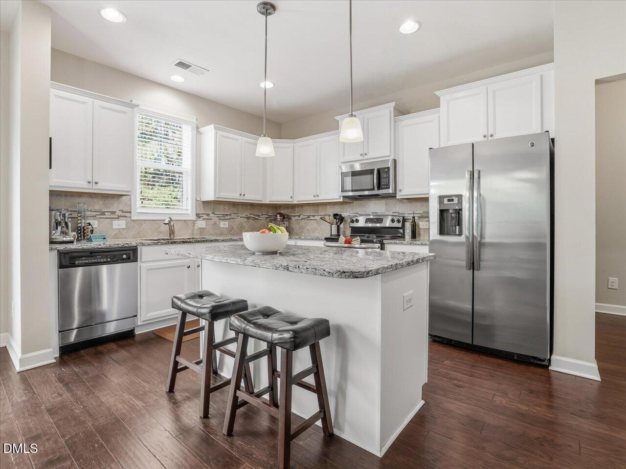 1200 Kinleywood Court Raleigh, NC 27603 - Photo 5 of 30 a kitchen with kitchen island white cabinets a refrigerator a oven a stove a dining table and chairs
