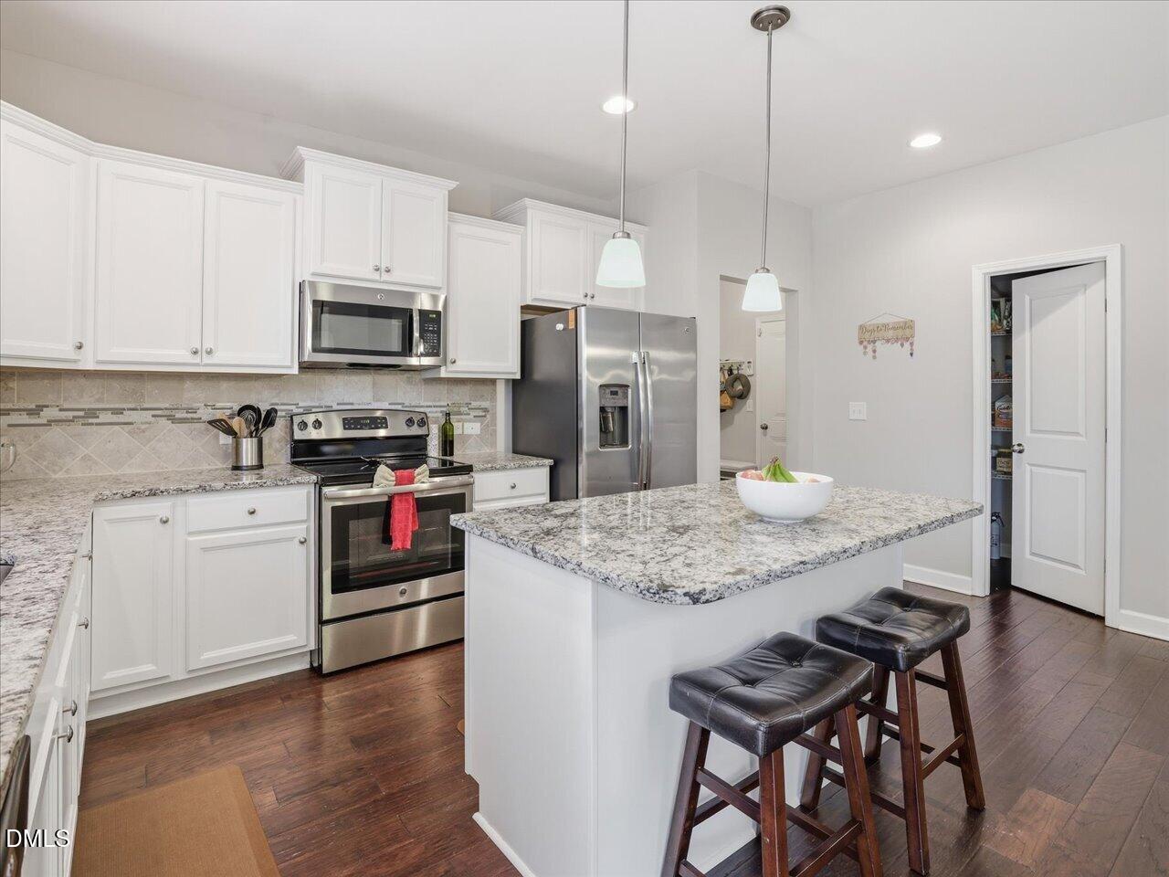1200 Kinleywood Court Raleigh, NC 27603 - Photo 7 of 30 a kitchen with stainless steel appliances granite countertop a stove top oven a refrigerator a sink and a dining table with wooden floor