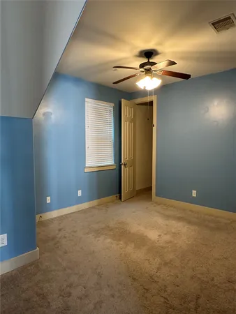 a view of an empty room with a chandelier fan