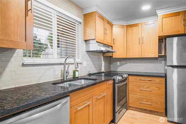 a kitchen with stainless steel appliances granite countertop a sink a stove and refrigerator