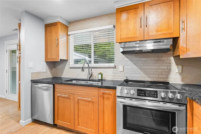 a kitchen with granite countertop wooden cabinets and a stove top oven