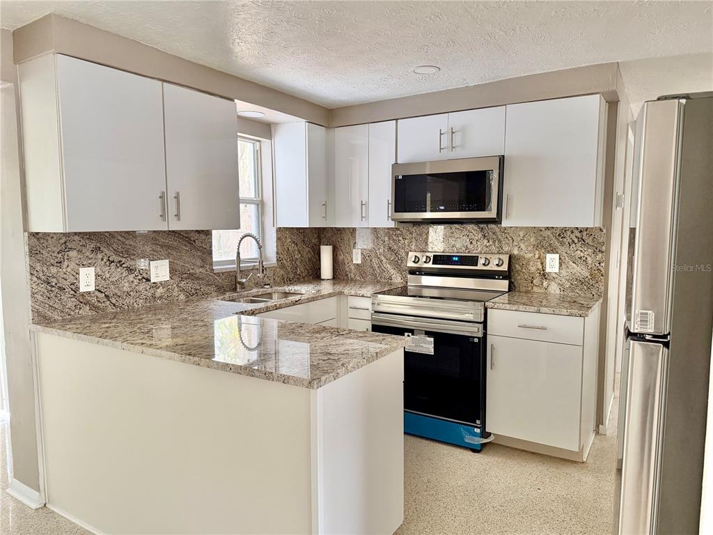 7441 Banner Street New Port Richey, FL 34653 - Photo 3 of 20 a kitchen with a refrigerator stove and microwave