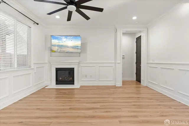 a view of an empty room with wooden floor a fireplace and a window