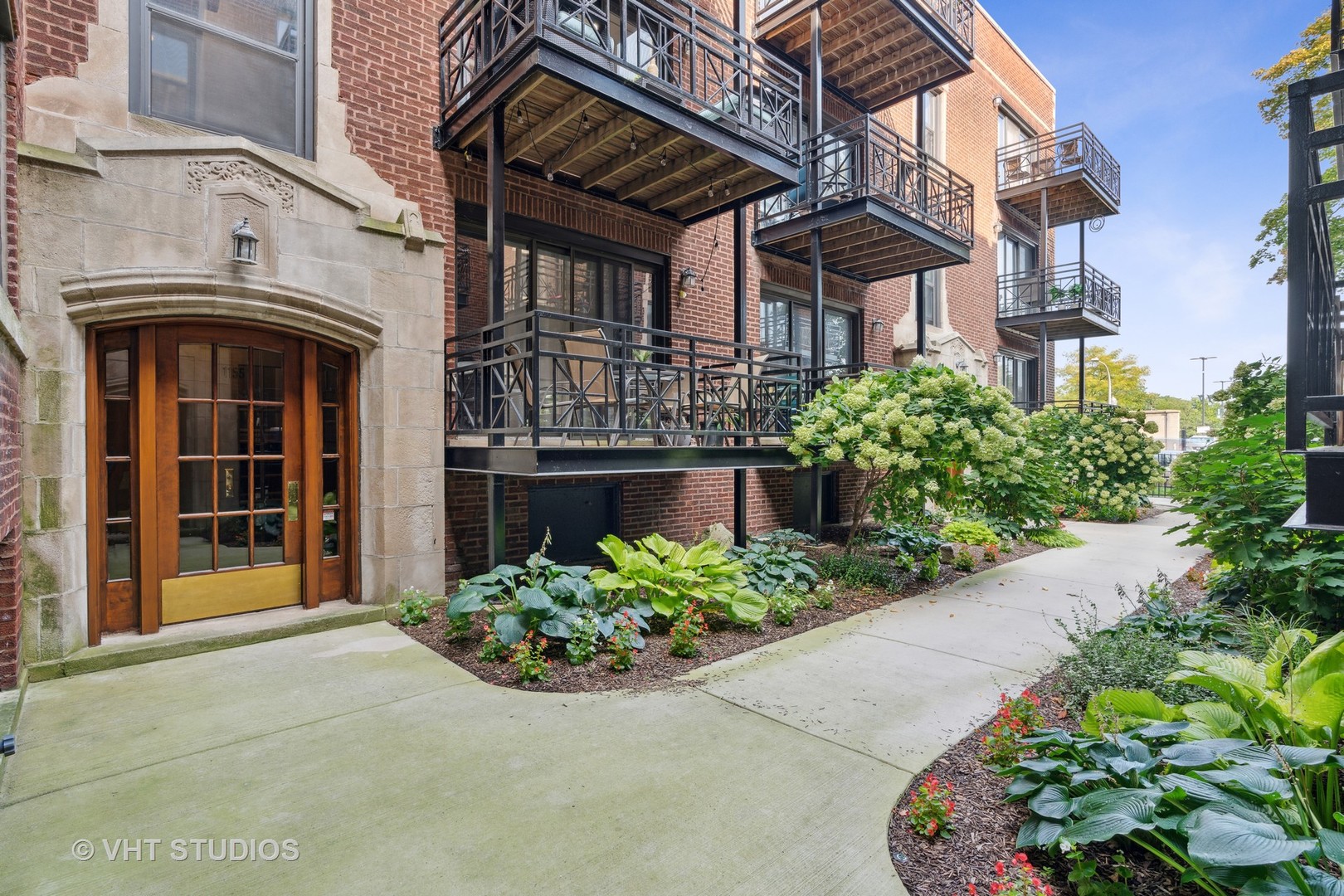 1155 West Grace Street, Unit 2N Chicago, IL 60613 - Photo 2 of 20 a front view of a multi story residential apartment building with a yard and potted plants