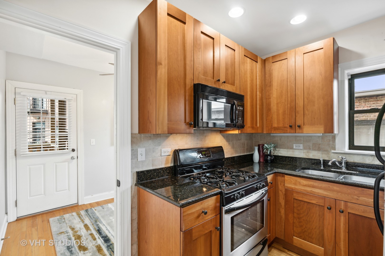 1155 West Grace Street, Unit 2N Chicago, IL 60613 - Photo 10 of 20 a kitchen with stainless steel appliances granite countertop a stove a sink and a microwave